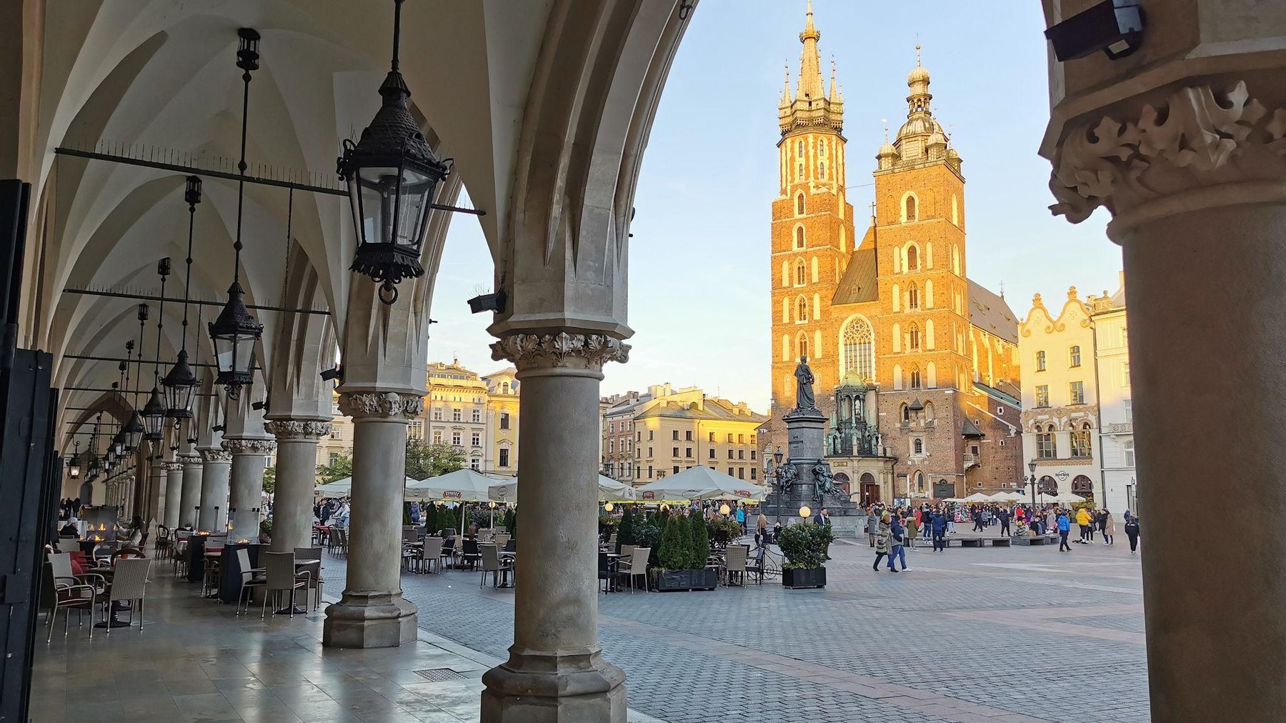 Krakow main square viewed through historic stone arches at golden hour