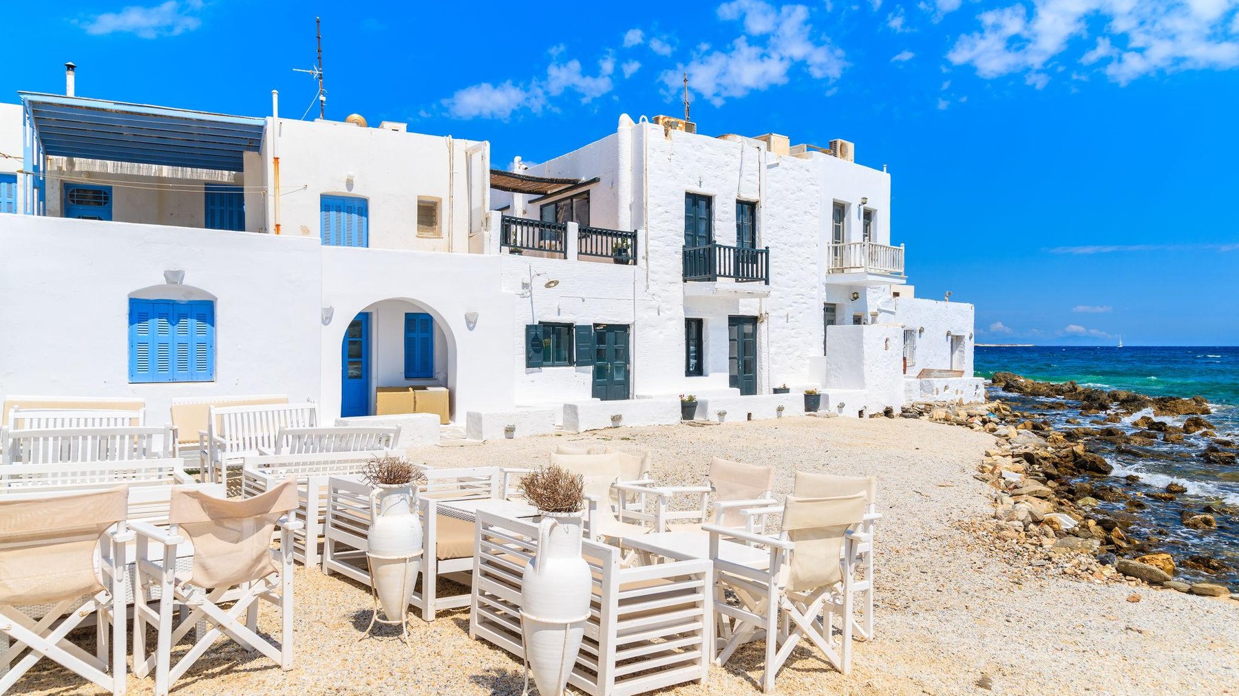 Whitewashed Greek island buildings beside bright blue water