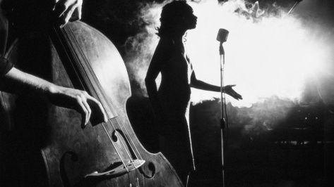 Black-and-white jazz club scene with singer, microphone, and upright bass